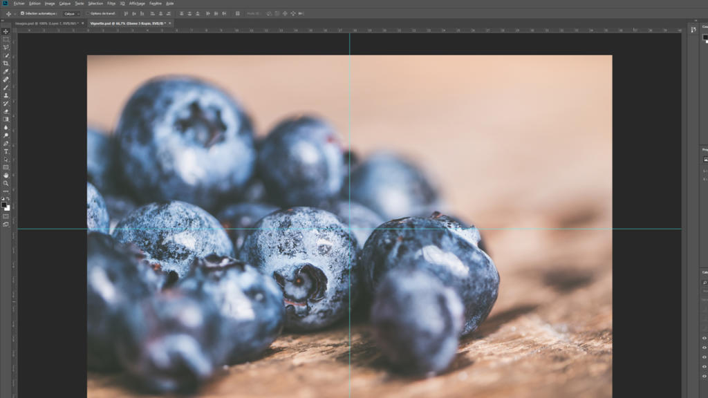 Un gros plan de myrtilles fraîches, parfaitement nettes et couvertes de gouttelettes, est posé sur une surface en bois. Présentée dans une interface Photoshop, l'image présente un subtil vignettage qui met en valeur leur couleur bleue éclatante sur un arrière-plan magnifiquement flou.