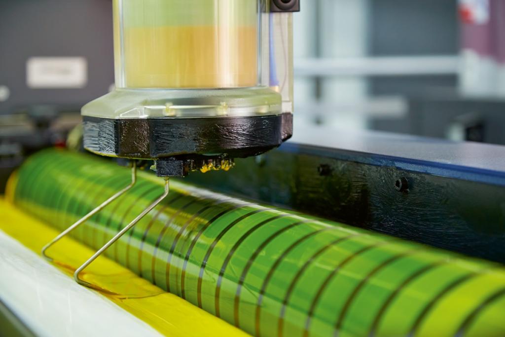 Un gros plan d'un cylindre de presse rotative vert et jaune en mouvement révèle les détails complexes de son mécanisme de guidage. Cette merveille industrielle fait partie d'un atelier de production offset et vous invite à une expérience unique de visite d'atelier de production offset.