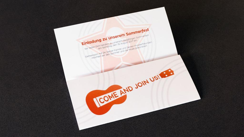 Une carte d'invitation à un événement estival sort de son enveloppe, telle un dépliant éclatant. Elle présente une illustration de guitare rouge avec le texte audacieux « VENEZ NOUS REJOINDRE ! » en rouge captivant, accompagné d'un texte allemand invitant chaleureusement les lecteurs à une célébration estivale.