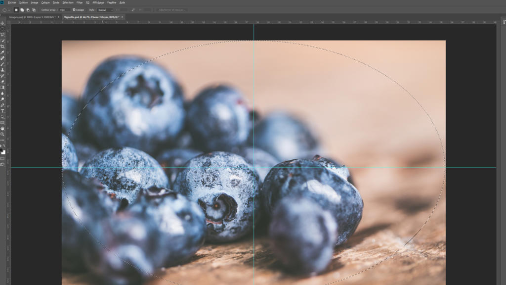 Gros plan d'une fenêtre Photoshop montrant une macrophotographie de myrtilles fraîches éparpillées sur une surface en bois. L'image est modifiée à l'aide de repères visibles et d'outils de sélection, et un subtil effet de vignettage est appliqué pour une mise au point optimale.