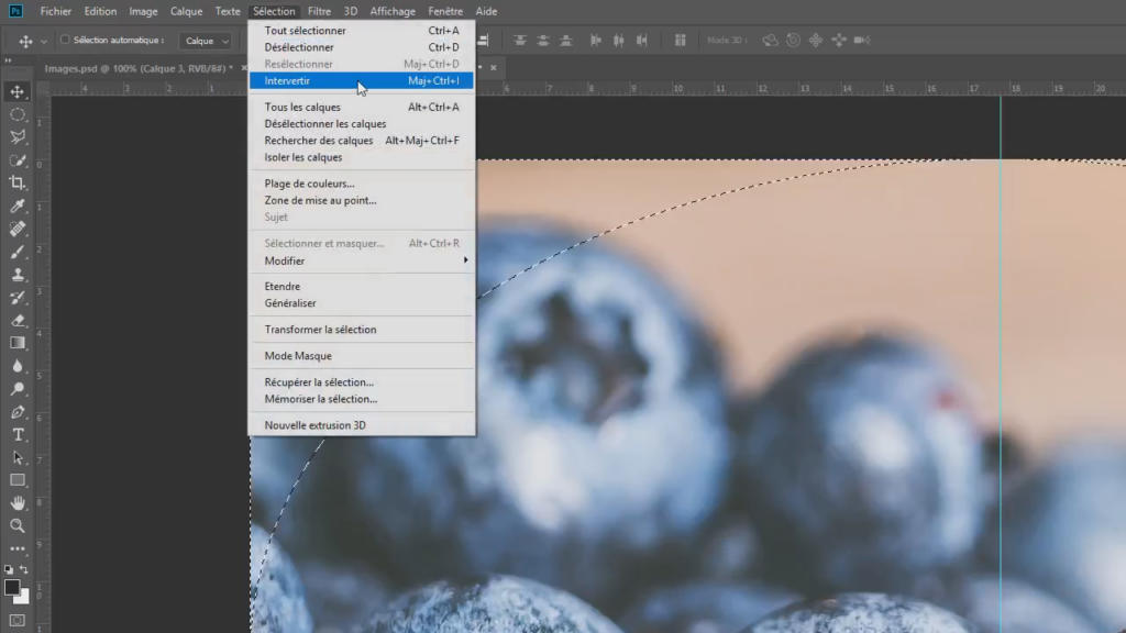 Gros plan d'une interface Photoshop avec un effet de vignetage appliqué, montrant un outil de sélection utilisé sur une image de myrtilles. Le menu en français est ouvert, affichant des options comme « Transformation manuelle » et « Tout sélectionner ».