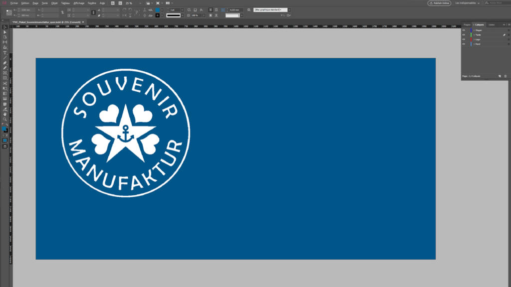 Une fenêtre de logiciel de conception affiche une image rectangulaire bleue, idéale pour la conception de bannières, avec un logo circulaire blanc à gauche. Ce logo comprend une étoile, une ancre et le texte « SOUVENIR MANUFAKTUR » entouré de cœurs.