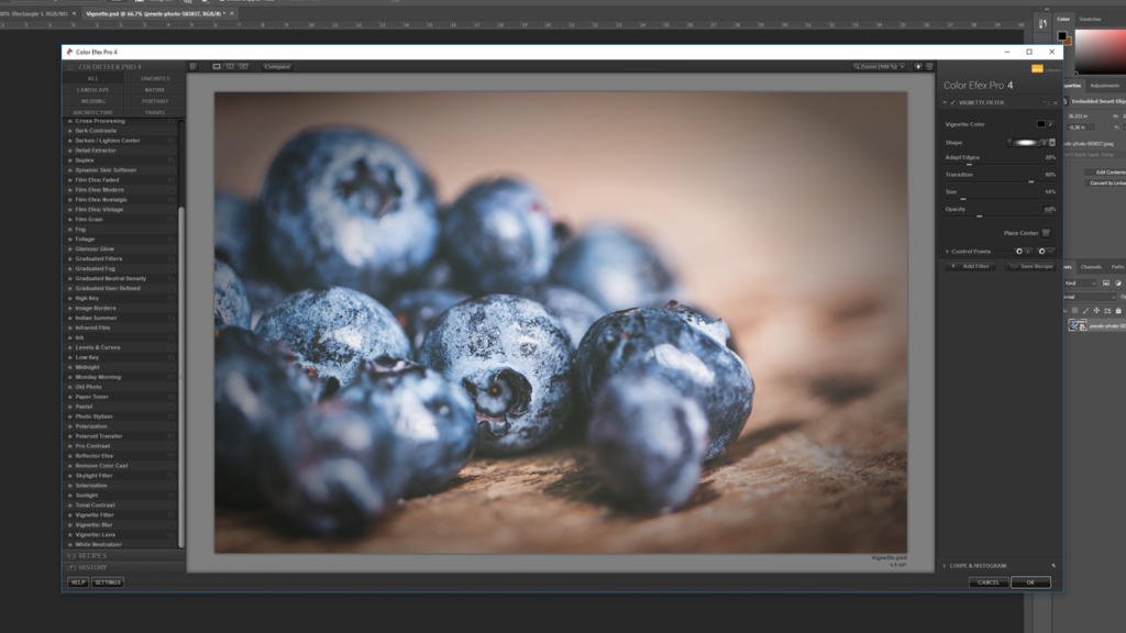 Un écran d'ordinateur affiche Photoshop avec son interface de retouche d'image, mettant en valeur une photo en gros plan de myrtilles. Des outils et options de retouche encadrent l'écran, tandis qu'un effet de vignettage rehausse subtilement les riches teintes de la baie.