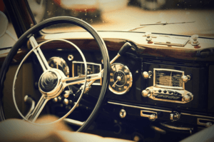 Un effet de vignette dans Photoshop sublime ce gros plan du tableau de bord d'une voiture ancienne, mettant en valeur le grand volant avec son centre métallique, ses cadrans classiques et sa radio analogique. La finition bois évoque une touche rétro et nostalgique.