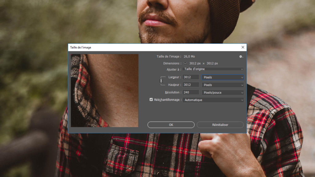 Une personne portant une chemise à carreaux rouges se tient dehors. L'image montre également un gros plan sur la fenêtre d'un logiciel de retouche d'image, où des options pour « détourer une image avec Photoshop » apparaissent, ainsi que des paramètres comme la taille du fichier, les dimensions et la résolution en français. L'arrière-plan est flou, laissant apparaître de la verdure.
