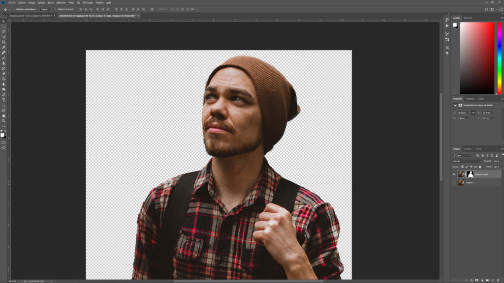 Une personne portant une chemise à carreaux et un bonnet marron regarde vers le haut, tenant une sangle sur son épaule dans l'interface Photoshop. L'image est prête à être modifiée grâce à un arrière-plan transparent, idéal pour détourer efficacement une image avec Photoshop.