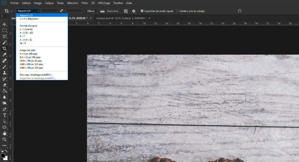 Un écran d'ordinateur affiche un logiciel de retouche photo en français. Une partie d'une surface en bois est visible dans la zone de travail, avec un menu ouvert proposant des options pour rogner une image et ajuster ses proportions et ses dimensions.