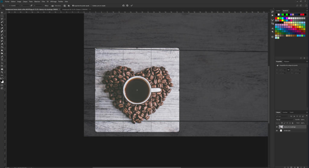 Une tasse à café est posée sur une surface en bois, entourée de grains de café disposés en forme de cœur. La vue plongeante met parfaitement en valeur la scène : une douce incitation à rogner une image avec soin tout en préservant son charme chaleureux.