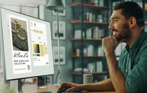 Un homme assis à un bureau, souriant, regarde un écran d'ordinateur affichant une publicité pour des bijoux. L'image montre des bagues, des sélections de couleurs et des options de texte. Une bibliothèque apparaît en arrière-plan.